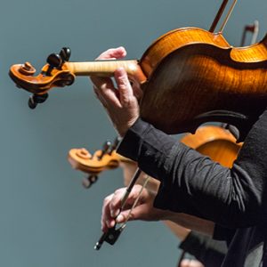 a closeup of two people playing violins